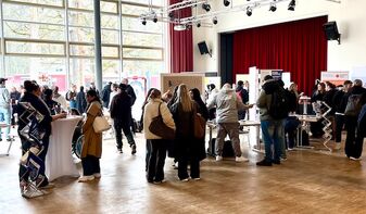 Teaserbild mit den Ständen der Messe und vielen interessierten Teilnehmenden